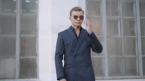 Stylish Young Man in Suit Puts on Sunglasses