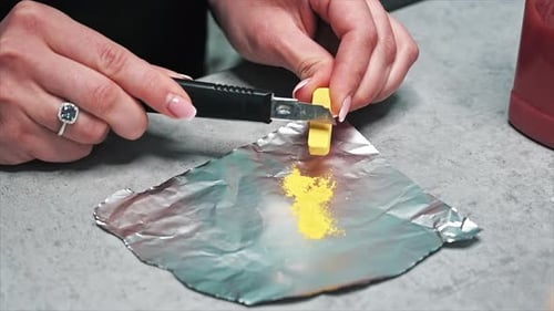 Hand made candles production, woman preparing a yellow dye for wax. Slow motion