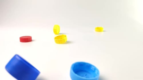 Colored Plastic Lids Fall on the Table on a White Background