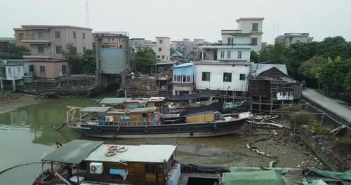 Aerial shot of an asian village located on a polluted river with maintenance boats moored