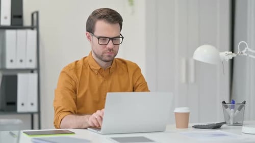 Man Working at Desk in Office on Laptop