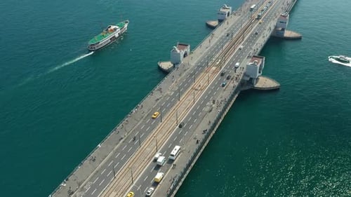 Galata Bridge Over Bosphorus Water with Boat and Car Traffic and Seagulls in Passing By, Aerial Tilt