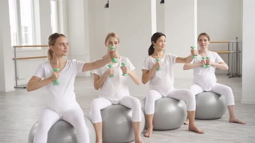 Pregnant Women Exercising with Dumbbells on Exercise Balls