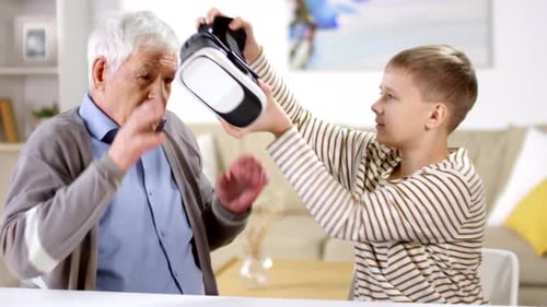 Boy Helping Senior Man With VR Headset