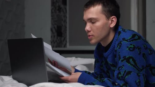 Young Adult Working on Bed With Laptop