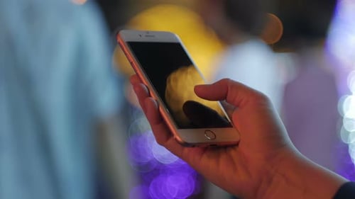 Hand Using Smartphone Reflecting Night Lights
