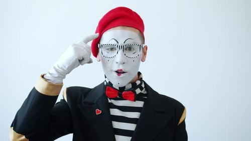 Ralenti d'un mime masculin montrant un geste fou de la main tordant un doigt à la tempe