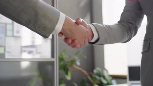 Handshake of Two Businessmen Standing in Corporate Office