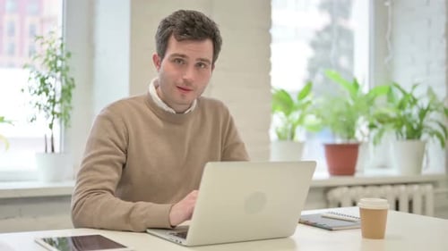 Man Showing Thumbs Up Sign While Using Laptop in Office