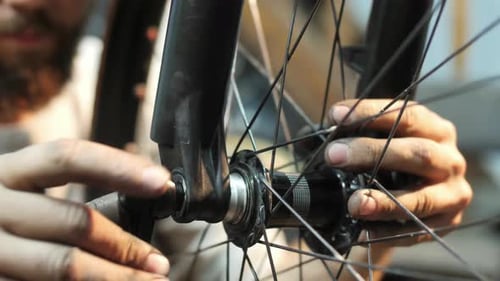 Bicycle Repairman Tightens Spokes on Wheel Close Up