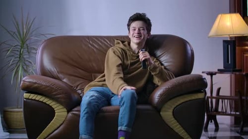 Teen Laughing and Watching Television on Couch