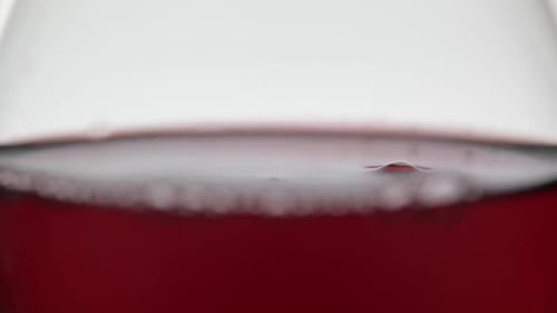 Close Up of a Drop Falling in Glass with Red Wine. Rose Wine on White Background