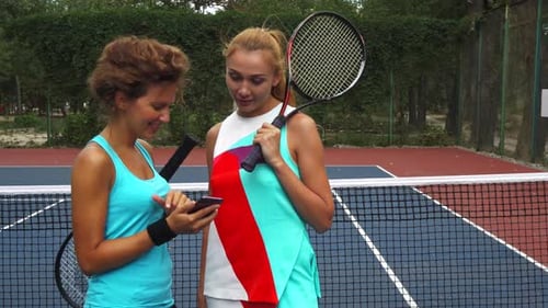 Women at Tennis Court Looking at Cell Phone