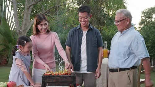 Happy Asian family having a barbecue-BBQ party together in the garden at home.