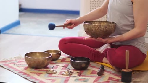 Woman Using Singing Bowls for Meditation in Bright Room
