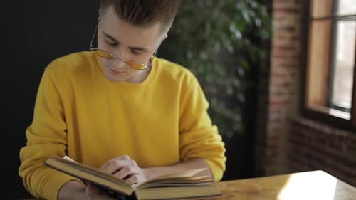 Young Adult Reading a Book at Table