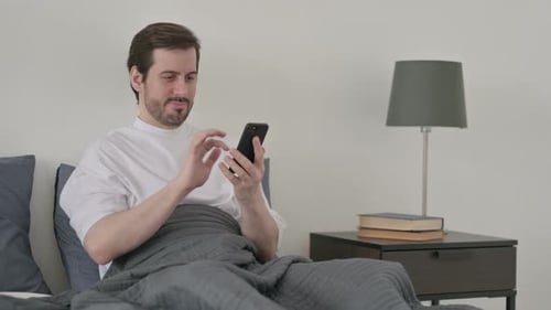 Man Lying in Bed Using Mobile Phone