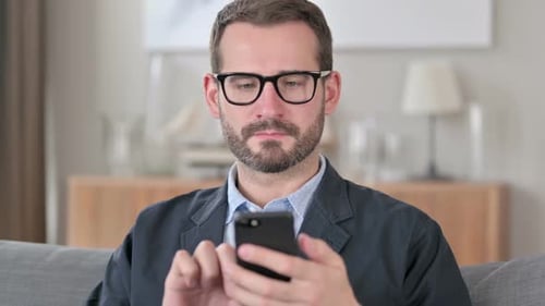 Man With Glasses Using Smartphone Indoors