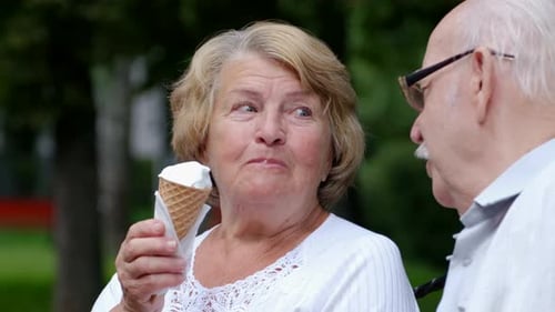 Grandfather and Grandmother Eat Ice Cream in a Cone