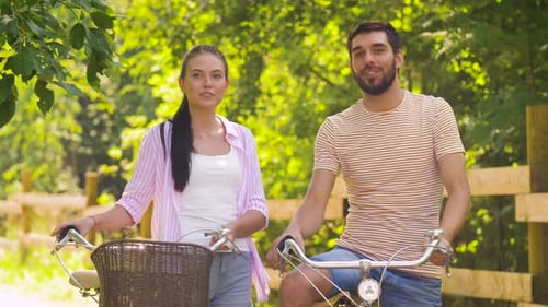 Happy Couple with Bicycles Talking at Summer Park
