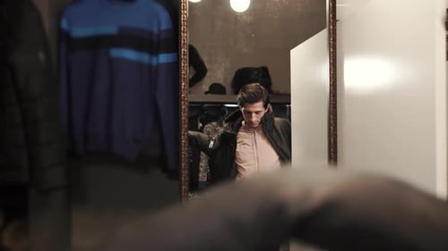 Man Tries on Jacket in Front of Mirror