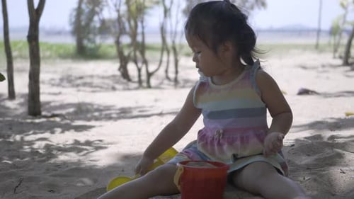 Happy little child girl playing with sand at resort tropical beach