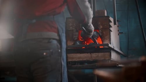 Blacksmith Workshop a Man Puts Metal Thing in the Oven Using Pincers