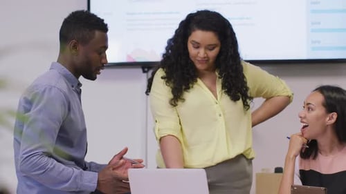 Happy diverse group of business people working together, using laptop in modern office