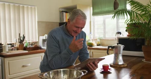 Senior Man Uses Tablet in Bright Kitchen