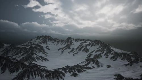 Aerial View of Snow-Capped Mountains Under Cloudy Sky