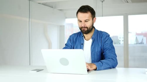 Bearded Man Working at Laptop in Office