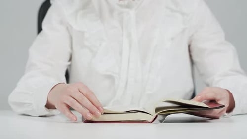 Person Reads a Book at a Desk Close Up