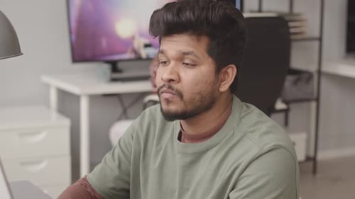 Focused Young Adult Working at Computer at Home