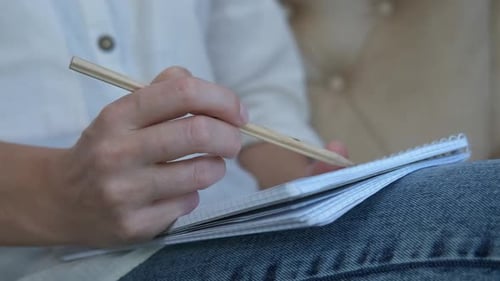 Person Writing in Notebook with Pencil Close Up