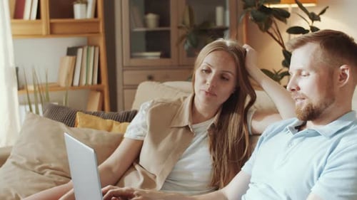 Couple Relaxing on Sofa Using Laptop at Home