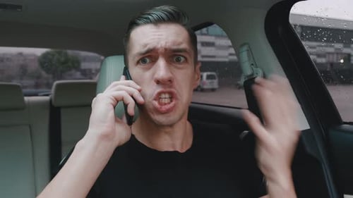 Upset Man Talking on the Phone in Car