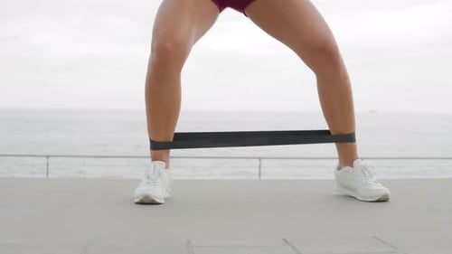 Woman Exercising Legs with Resistance Band by Ocean