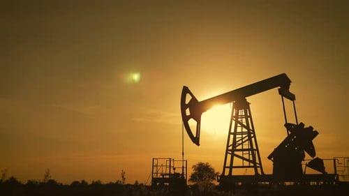 Silhouette of Working Oil Pump From Oil Field at Sunset. The Industrial Equipment.