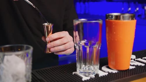 Bartender Pouring Liquid into Jigger on Bar