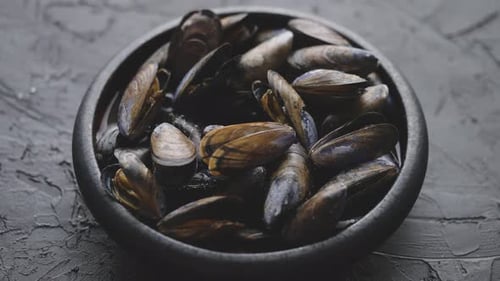 Fresh and Raw Sea Mussels in Black Ceramic Bowl Placed on Dark Stone Background