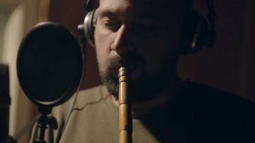 Mann spielt Flöte im Studio