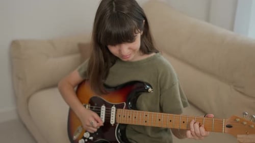 Girl Plays Electric Guitar at Home on Couch