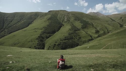 Female Traveler Sits on Hill Above the Mountain Gorge. Young Woman Highland Mountain Landscape