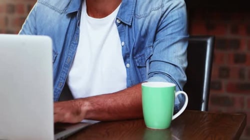 Mann trinkt Kaffee, während er am Laptop arbeitet