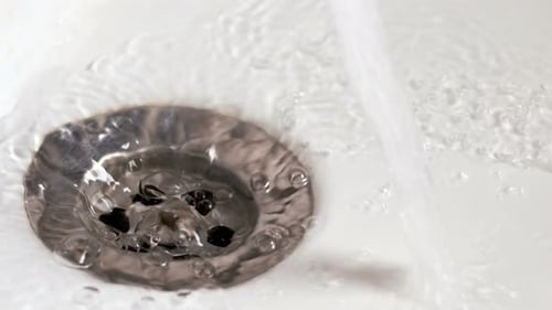 Water Flowing Over Chrome Sink Drain Close Up