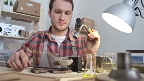 Man Soldering Metal Craft at Workbench