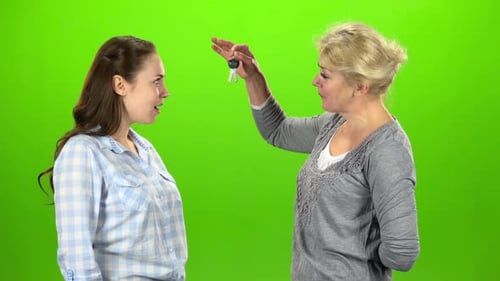 Une femme donne les clés à sa fille. Écran vert. Vue latérale