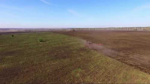 Aerial view of Tractor plow in a huge field. Summer, sunny day.