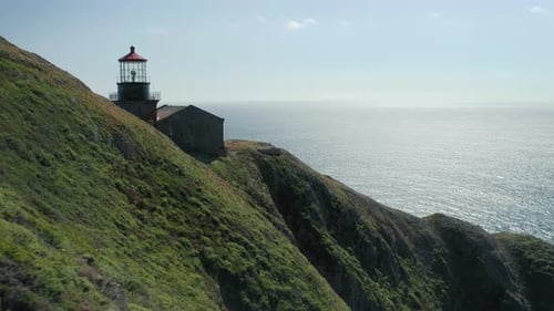Flying Over the Green Island Revealing the Historical Lighthouse at the Edge