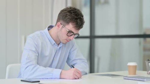Man Writing at Desk in Office